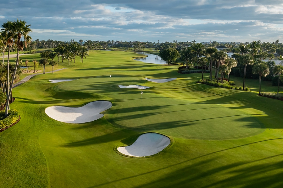 Aerial shot of Sailfish Point fairways stretching toward the coastline under soft clouds.
